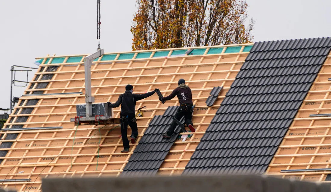 Couvreurs posant des tuiles sur une toiture neuve